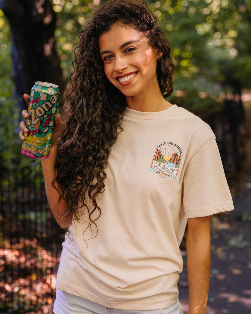 Girl holding AriZona Iced Tea can while wearing the AriZona x GOAT USA Desert GOAT T-Shirt