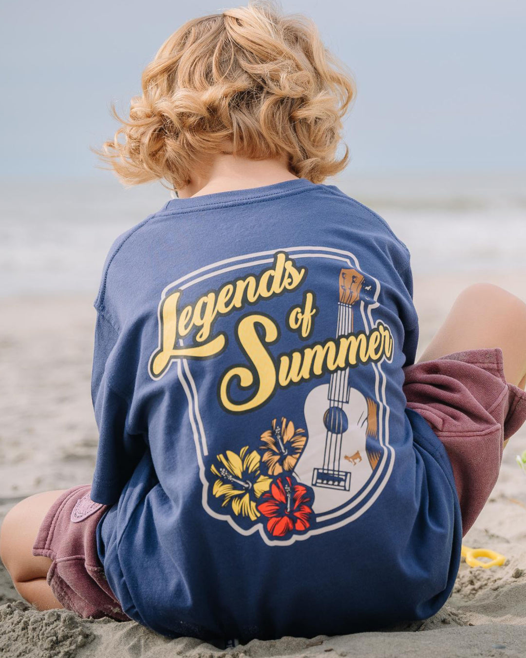 Kid sitting down playing in the sand