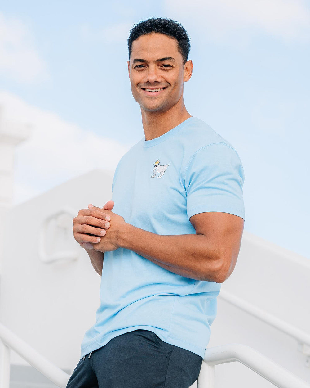 Male model leaning on railing wearing carolina blue WG T-Shirt#color_carolina-blue